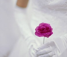 A bride holding a dark pink rose